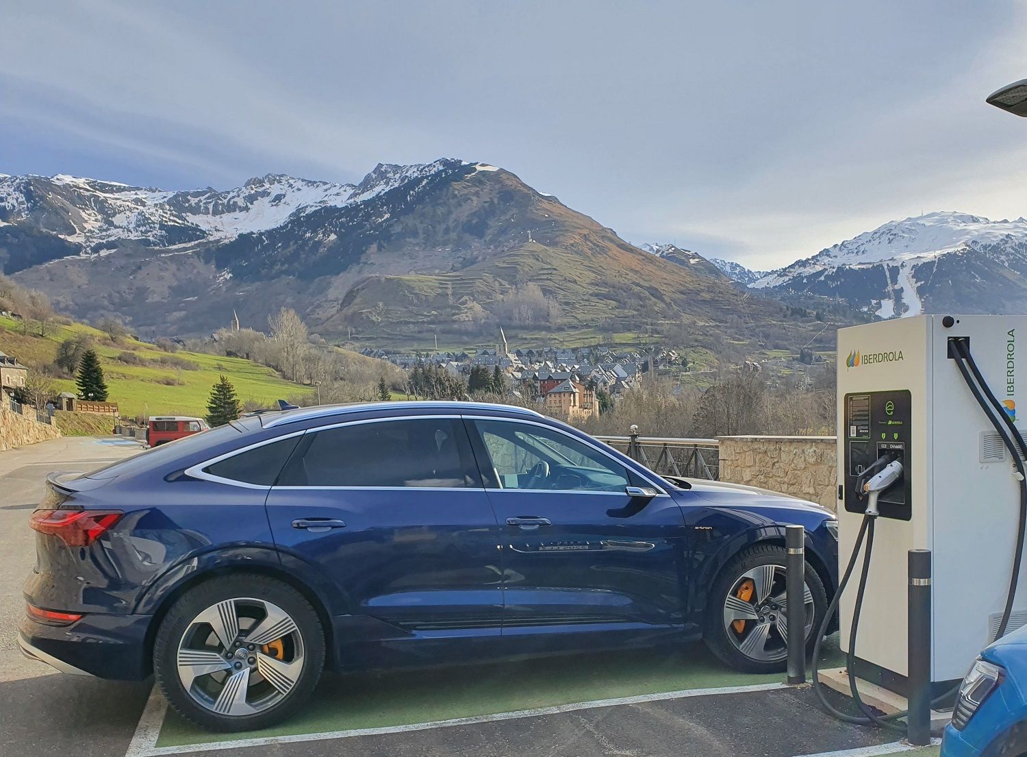 Vehículo eléctrico cargando junto a un paisaje de los Pirineos